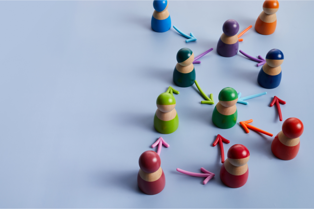 Vemos alguns bonecos coloridos representando pessoas com setas que apontam um para os outros, representando um pouco da diversidade e da cooperação entre diferentes talentos dentro de uma organização.